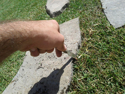 Taglio del prato con la sagoma della mattonella di porfido